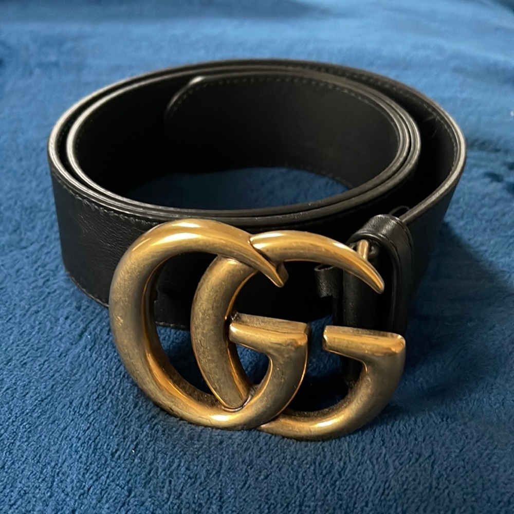 A black Gucci belt with gold Gucci symbols